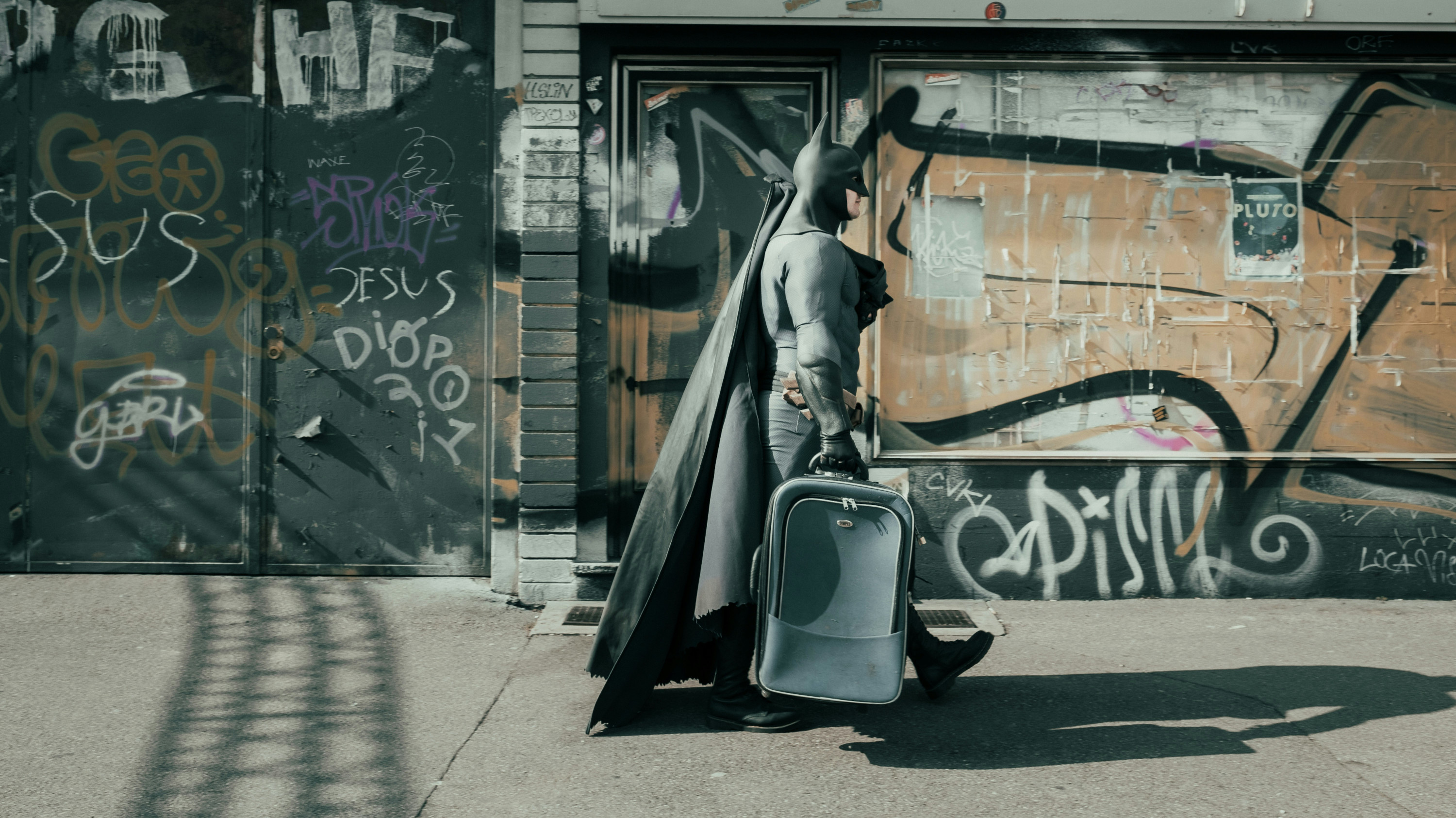 Batman on the move, carrying a roller bag down the street