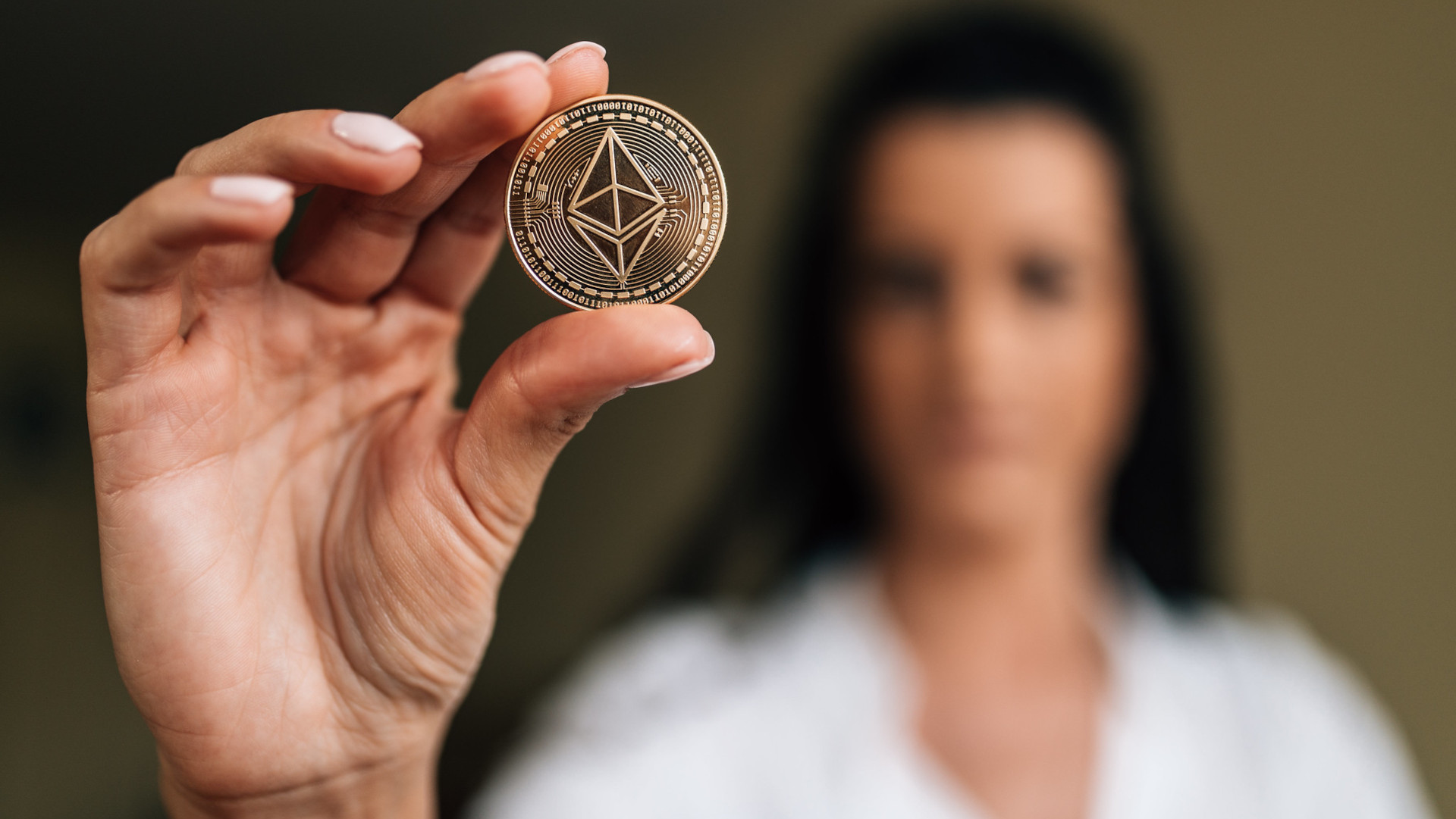 Woman holding up a physical ether coin