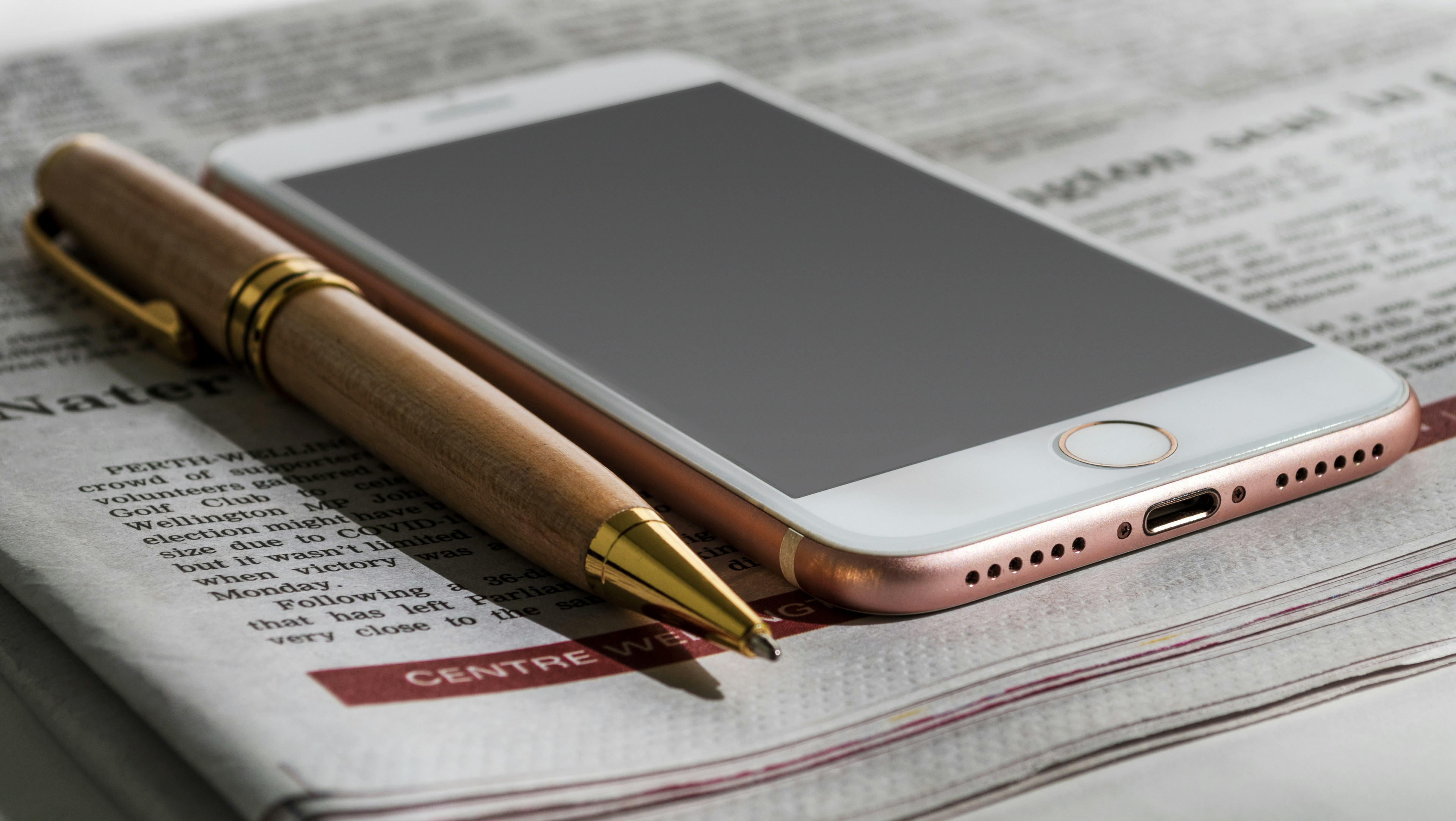 Stack of newspapers with a smartphone and a pen on top